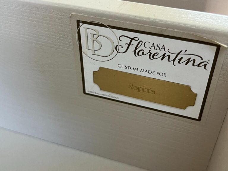 A close-up of a label on a piece of furniture that reads "Casa Florentina, Custom Made for Sophia" in gold text. The manufacturer's logo is also visible.