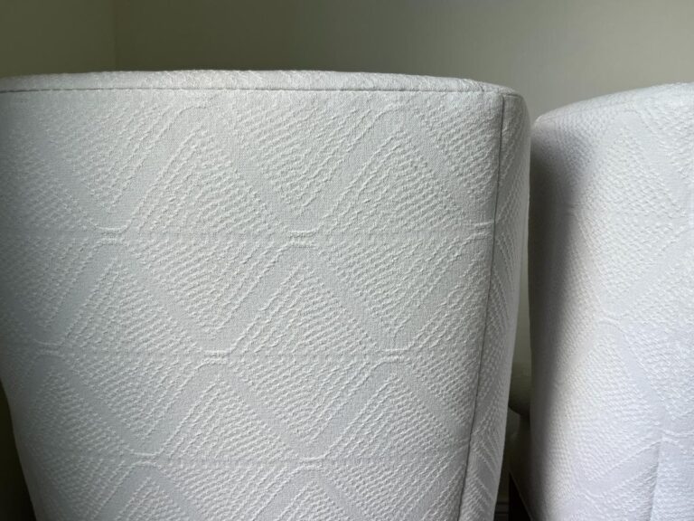 Close-up of the textured surface of two white upholstered chairs, showing a pattern of intersecting diagonal lines.