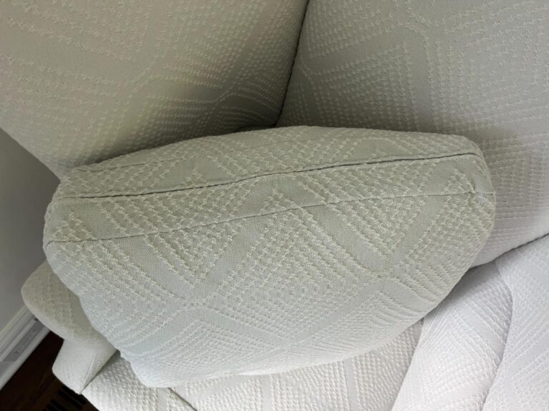 Close-up of a white textured couch with a detached cushion that exhibits a geometric pattern.