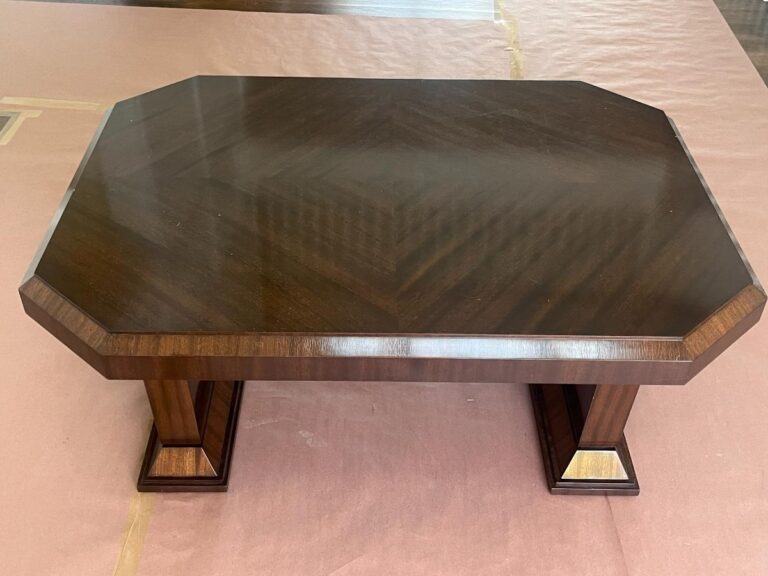 A polished, dark wooden coffee table with a hexagonal top and rectangular legs.