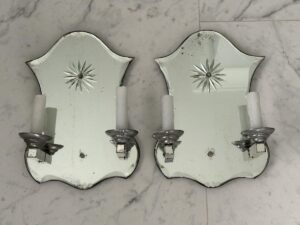 Two Vintage Mirrored Double Arm Sconces with candle holders are mounted on a marble surface, each featuring an etched starburst design on the mirrored backplates.