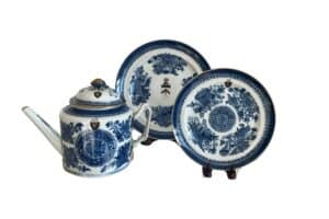 Antique blue and white porcelain tea set with intricate patterns, including a teapot and two plates on stands.