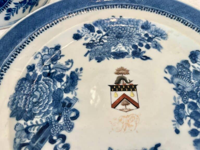 Blue and white ceramic plate with intricate floral patterns and a central crest featuring a tree, animal, and pear symbols.