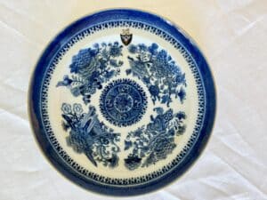 A blue and white porcelain plate with intricate floral and geometric patterns, displayed on a white surface.