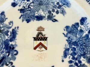 Blue and white ceramic plate with floral patterns and a central coat of arms featuring pears and stars.