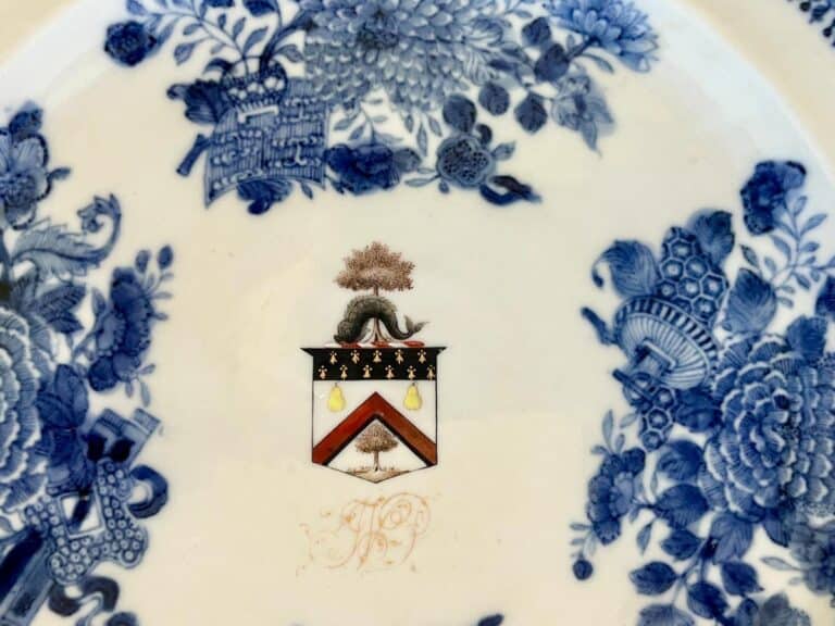 Blue and white ceramic plate with floral patterns and a central coat of arms featuring pears and stars.