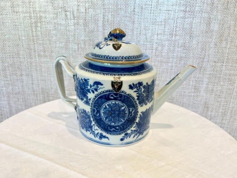 Blue and white porcelain teapot with intricate floral design on a textured background.