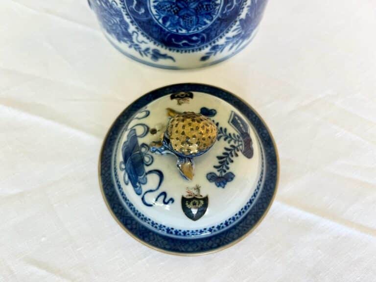 Small porcelain lid with intricate blue floral designs and a gold accent on top, placed on a white surface.