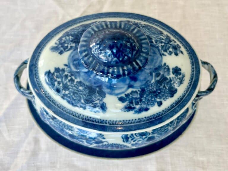 A blue and white porcelain tureen with floral patterns, featuring two handles and a lid, placed on a light-colored surface.