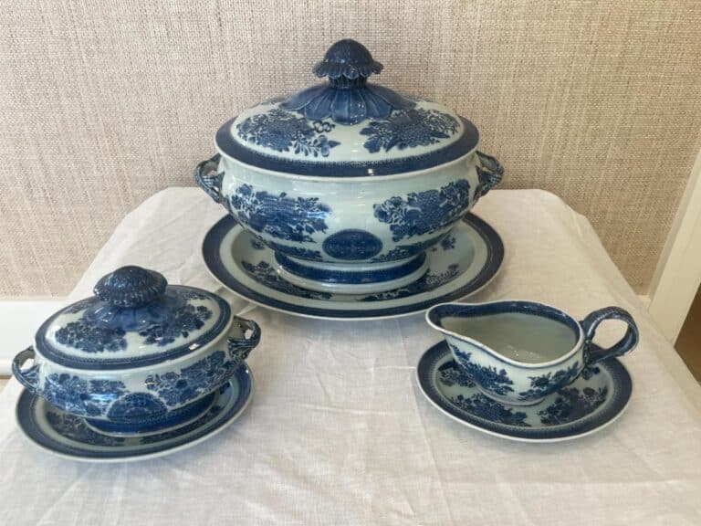 A set of blue and white porcelain dinnerware on a table: a large lidded tureen, a smaller lidded bowl, and a gravy boat with a saucer, featuring floral patterns.