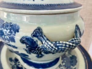 Close-up of a ceramic pot with blue floral patterns and a handle in the shape of a claw.