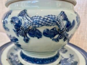 A close-up of a ceramic vase with blue and white floral patterns and a checkered ribbon handle.