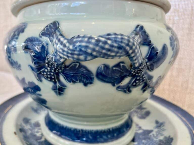 A close-up of a ceramic vase with blue and white floral patterns and a checkered ribbon handle.