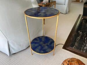 Pair of gold-framed round tables with blue stone surfaces, featuring two tiers, placed on a lightly carpeted floor.