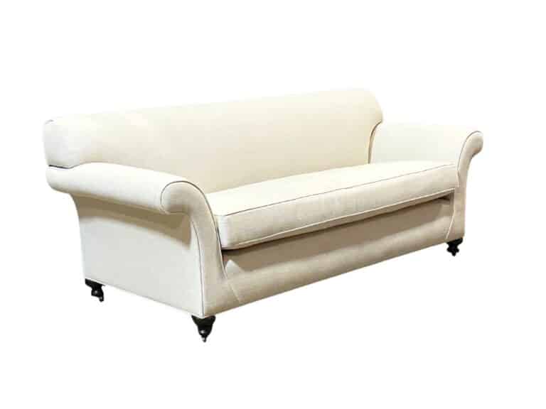 A beige fabric sofa with rolled arms and black cylindrical legs against a white background.