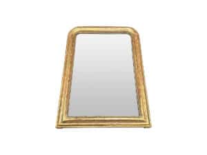 A trapezoidal gold-framed mirror with a reflective surface set against a white background.