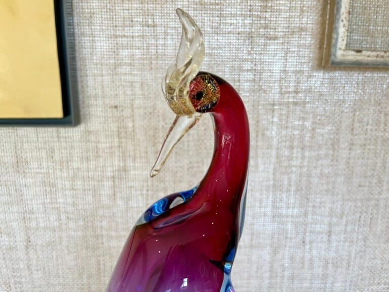 The Barbini Murano Bird of Paradise Italian Art Glass Sculpture features a stylized bird with a red body, clear beak, and ornate head, set against a textured background.