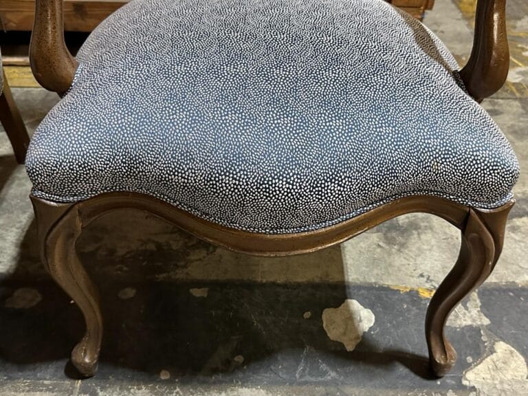 Ornate wooden chair with curved legs and a speckled black and white cushion.