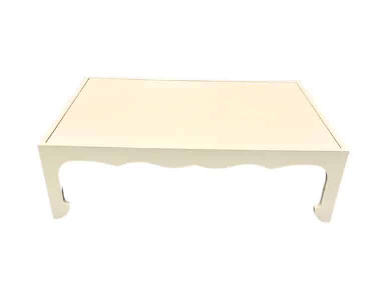 Rectangular coffee table with a beige top and decorative curved legs against a white background.