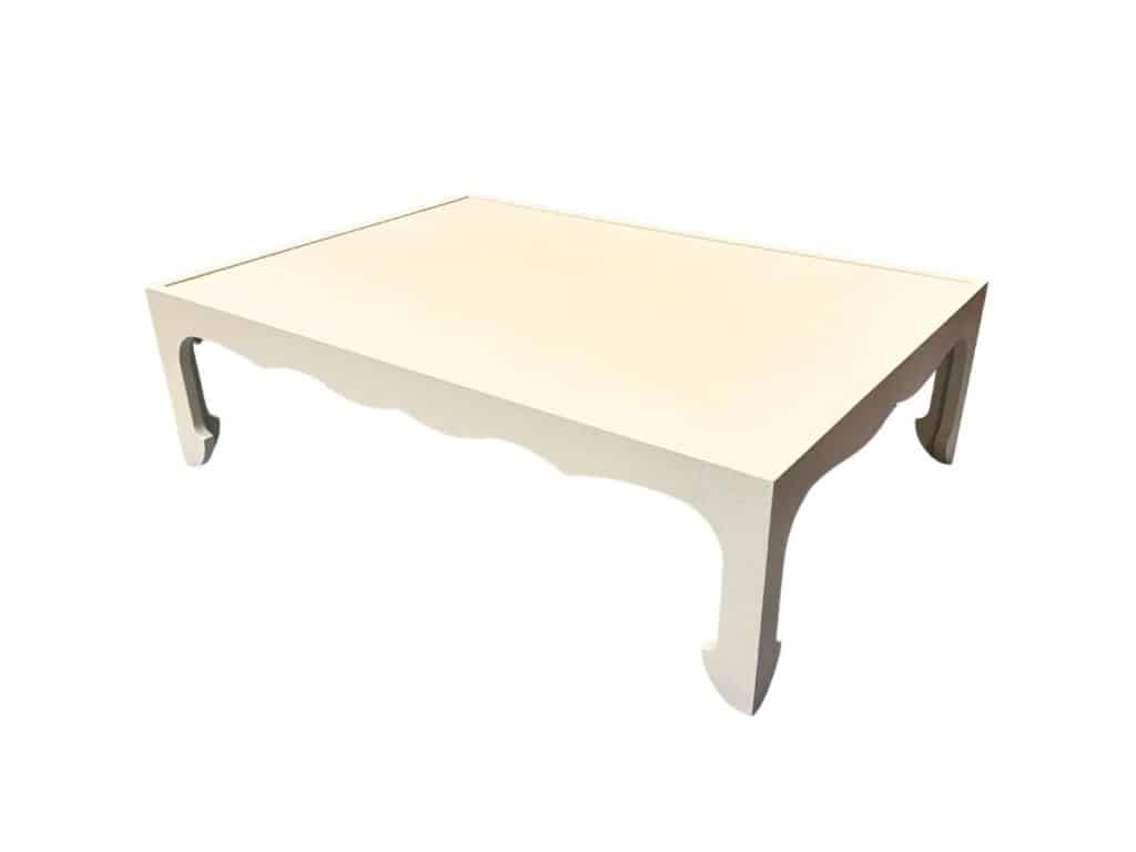 A light-colored, rectangular coffee table with decorative scalloped edges and curved legs, set against a white background.