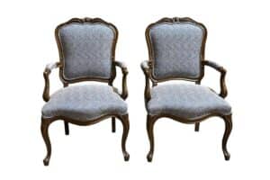 Two vintage-style wooden armchairs with ornate carving details and light gray upholstered cushions.