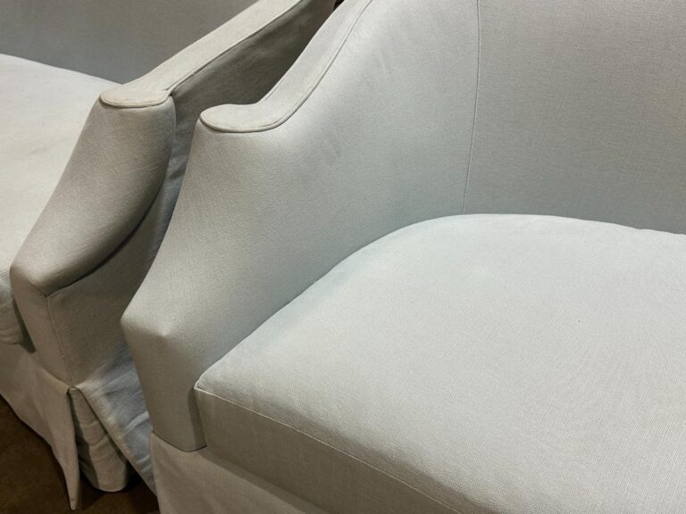 Two light gray upholstered armchairs with curved armrests.