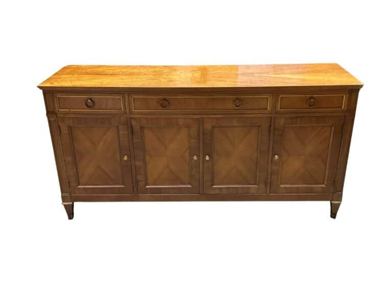 A wooden sideboard with three top drawers and four cabinet doors, featuring a natural wood finish and brass knobs.