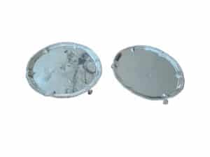 Two circular silver serving trays with decorative edges placed side by side on a white background.