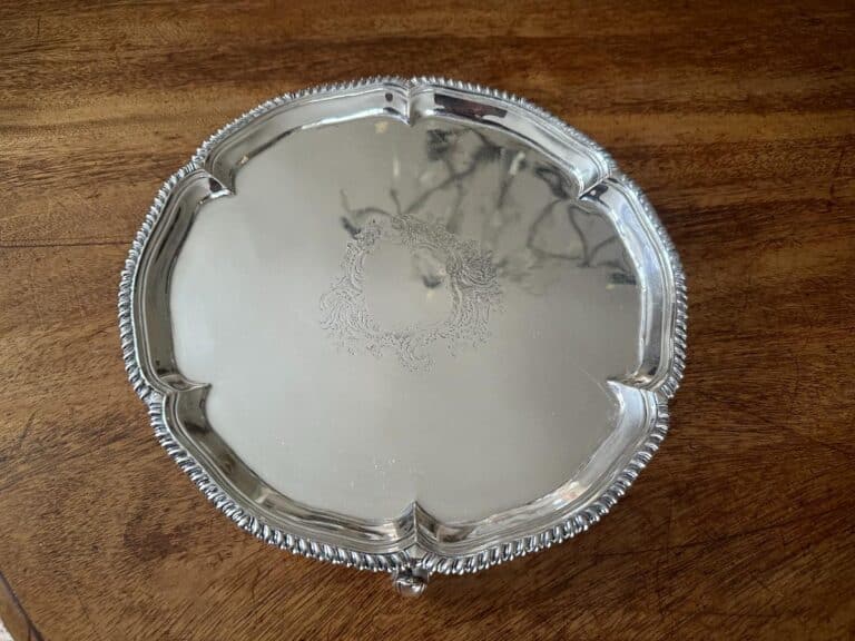 Silver serving platter with ornate detailing on a wooden table.