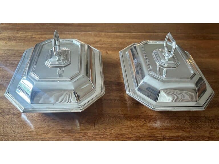 Two silver serving dishes with lids on a wooden surface.