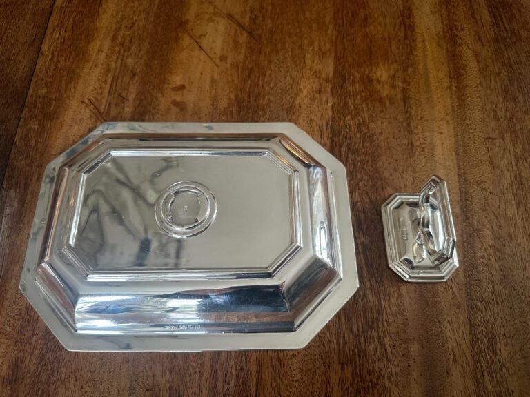 Two silver platters, one large and one small, with octagonal shapes, placed on a wooden surface.