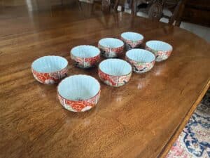 Eight decorative ceramic bowls with floral patterns are arranged on a wooden table.