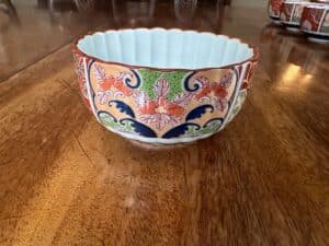 Decorative bowl with floral patterns in red, green, and blue sits on a wooden table.