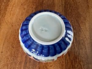 Bottom view of a ceramic bowl with blue outer sides and a white base, placed on a wooden surface.