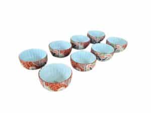 Eight ceramic bowls with intricate red and blue designs arranged in two rows.