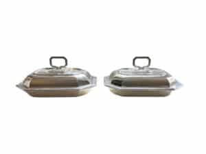 Two identical silver chafing dishes with lids and handles placed side by side.