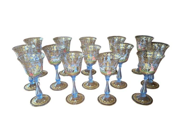 Set of twelve ornate blue and gold wine glasses with intricate designs and slender stems.