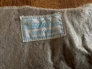 A fabric label with "Cashmere" and "New York" embroidered in blue on a textured gray material.