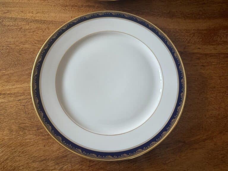 A white porcelain plate with a blue and gold ornate border on a wooden table.