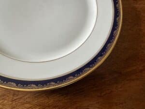 Close-up of an ornate dinner plate with blue and gold detailing on a wooden table.