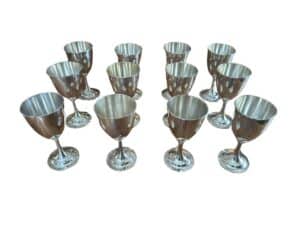 Twelve silver goblets arranged in three rows on a white background.