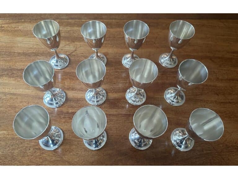 Twelve silver goblets arranged on a wooden surface, viewed from above.