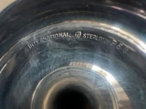 Close-up of a shiny, reflective goblet with "INTERNATIONAL STERLING P58" engraved from a set of 12 by International Silver Co Sterling.