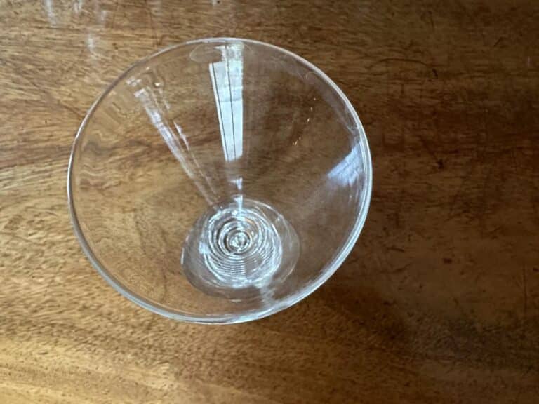 Empty clear martini glass on a wooden surface, viewed from above.