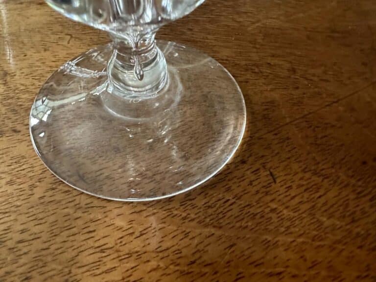 Close-up of a glass stem resting on a wooden table.