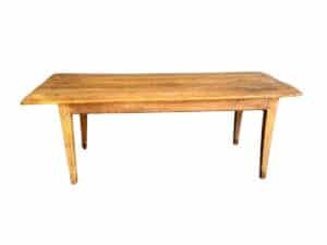 The Antique Pine Farm Table is a long, rectangular wooden table with a rustic finish and four straight legs.