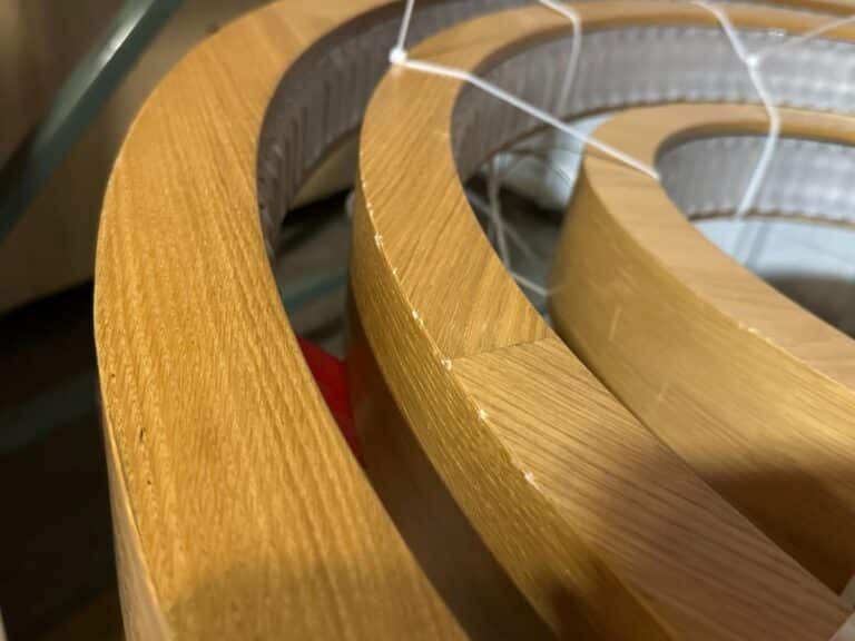 Close-up of stacked rolls of wood veneer edging, showing the texture and grain pattern.