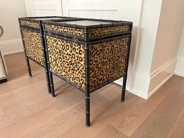 Two rectangular ottomans with black frames and leopard print fabric stand on a hardwood floor near a white wall.