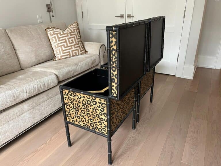 Open storage bench with leopard print design next to a beige sofa and patterned pillows on a hardwood floor.