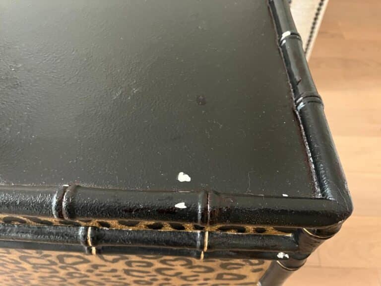 Close-up of a black cabinet with a leopard print design and some chipped paint on the corner.